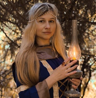 Heathen woman in the woods holding a candle lamp